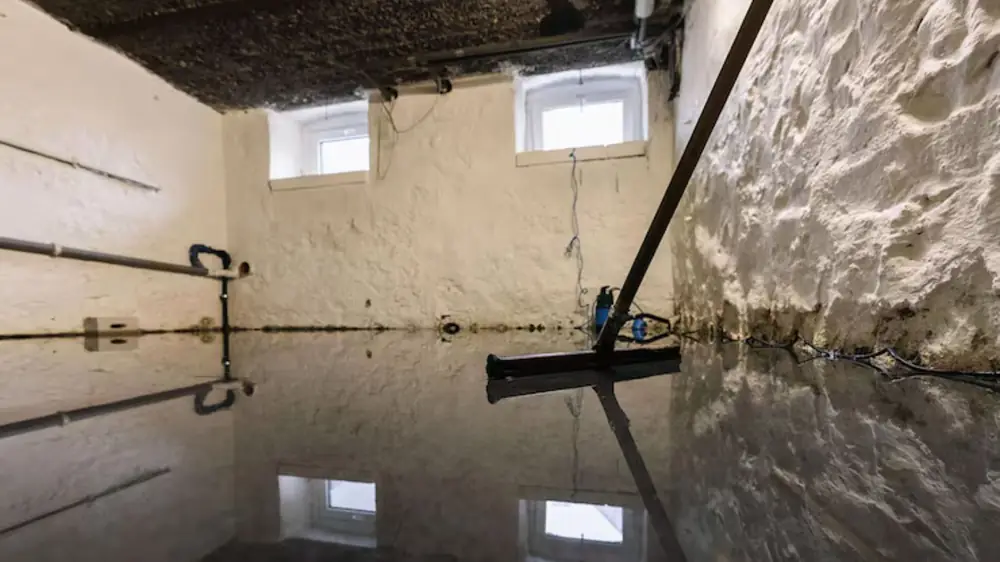 Basement with water on the floor and a squeegee leaning on the wall