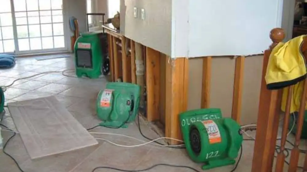 Air movers drying a wet floor and opened wall cavity